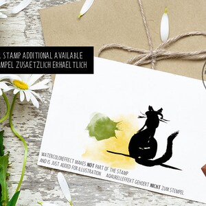 May include: A black cat rubber stamp design with watercolor effect, on a white card. The card has text that says "Thank you for your" and "Cat rubber stamp additional available". Daisies and a brown envelope with twine are in the background.