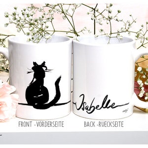 May include: Two white ceramic mugs. One mug features a black silhouette of a cat and the text "FRONT - VORDERSEITE". The other mug has the name "Isabelle" in black script and the text "BACK - RUECKSEITE".