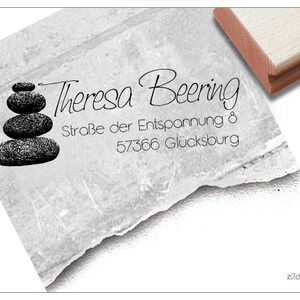 May include: A personalised stamp featuring the name "Theresa Beering" in cursive, address details, and a zen stone design. The stamp has a wooden handle and is suitable for personal or business applications.