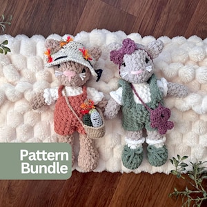 May include: Two crocheted animal dolls with yarn textures. The left doll wears a cream sun hat with orange accents, a white shirt, and rust-colored overalls with a small basket. The right doll wears a purple bow, white shirt, green overalls, and a purple bag.