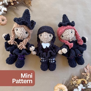 May include: Three crocheted dolls featuring black outfits and hats. The left doll has tan hair, the center doll has black hair and a white collar, and the right doll has pink hair. Each doll has black button eyes and a ruffled skirt design.