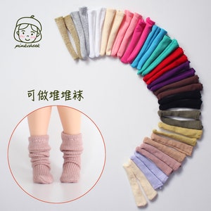 May include: A variety of colorful doll socks in a semi-circle, with a pair of pink doll socks on a doll's legs in the center. The text "可做娃娃袜" is visible in the image.