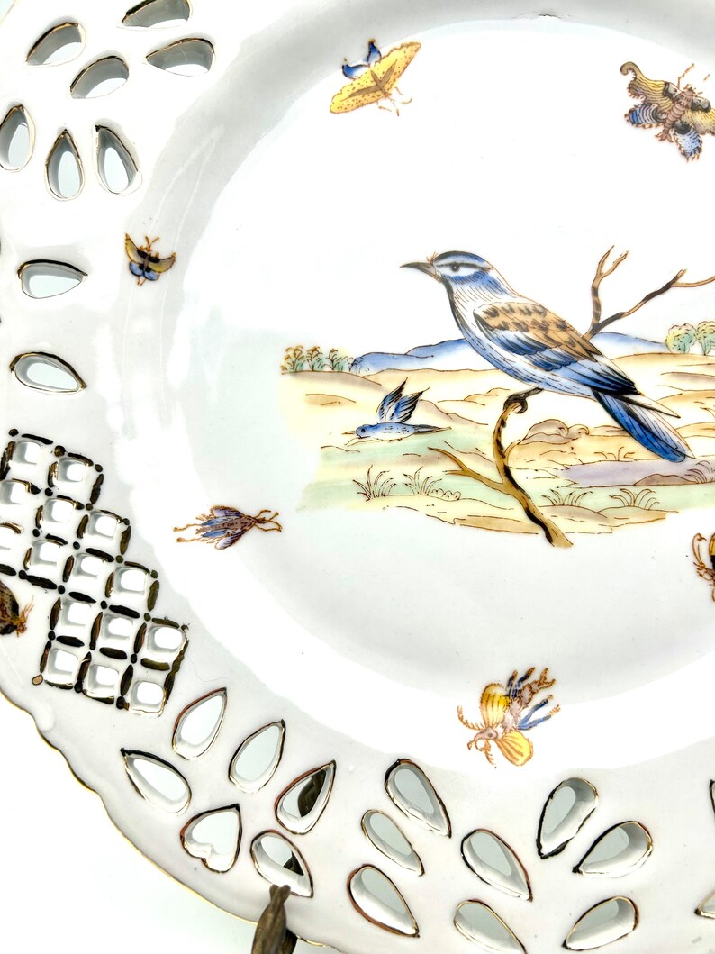 May include: White porcelain plate with a decorative openwork border and a hand-painted bird and butterfly design. The plate features a detailed illustration of a blue and brown bird perched on a branch, with several butterflies scattered around the rim.