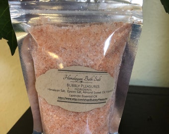 May include: A clear plastic bag filled with pink Himalayan bath salt. The bag has a label that reads "Himalayan Bath Salt" and "Bubbly Pleasures". The label lists the ingredients: Himalayan Salt, Epsom Salt, Almond Sweet Oil, Vitamin E, and Lavender Essential Oil. The label also includes a website address: https://www.etsy.com/shop/BubblyPleasures