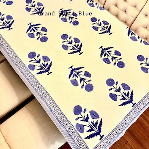May include: A white tablecloth with a blue floral pattern and a blue and white border. The text "Grand Petit Blue" is visible in the center of the tablecloth.