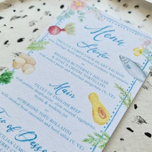 May include: A watercolour menu card with a blue and white border. The menu features a starter of Treacle Cured Loch Duart Salmon or Roasted Butternut Squash & Goat's Cheese Tortellini, a main course of Fillet of English Beef or Aubergine Tofu Rollatini, and a trio of desserts: Sicilian Lemon, Raspberry, and Salted Caramel.