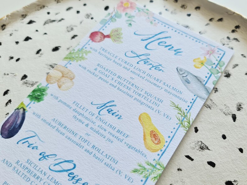 May include: A watercolour menu card with a blue and white border. The menu features a starter of Treacle Cured Loch Duart Salmon or Roasted Butternut Squash & Goat's Cheese Tortellini, a main course of Fillet of English Beef or Aubergine Tofu Rollatini, and a trio of desserts: Sicilian Lemon, Raspberry, and Salted Caramel.