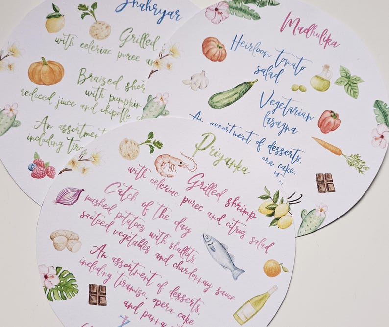 May include: Three white round paper place cards with watercolour illustrations and handwritten text. The place cards list the menu items for a wedding reception. The first place card says "Shahryar" and lists "Grilled Shrimp with celeriac puree and citrus salad". The second place card says "Madhulika" and lists "Heirloom Tomato Salad, Vegetarian Lasagna, An assortment of desserts, one cake". The third place card says "Priyanka" and lists "Catch of the Day, Mashed potatoes with shallots, sauteed vegetables and Chardonnay sauce, An assortment of desserts, including tiramisu, opera cake, and panna cotta".