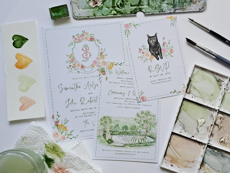 May include: Wedding invitation suite with watercolor illustrations. The main invitation features a floral crest with the names Samantha Arlys and John Robert. The RSVP card features a black cat with floral accents. The ceremony card features a watercolor illustration of a venue with a green lawn and trees.