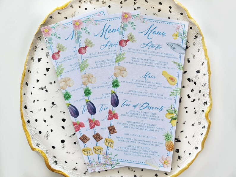 May include: A set of three watercolour menus with floral borders and illustrations of food. The menus list a starter, main course, and a trio of desserts. The text on the menus reads: "Menu Starter", "Treacle Cured Loch Duart Salmon", "Roasted Butternut Squash", "Main", "Fillet of English Beef", "Trio of Desserts", "Sicilian Lemon Tart", "Raspberry Creme Brulee", "Pineapple Tarte Satin", "Chillian Themes Selection".