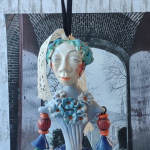 Clay art doll. Dangling doll sculpted from stoneware pottery clay. Dressed in baroque style in puffy pants with flounces and ruffles.