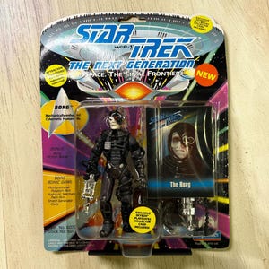 May include: Star Trek: The Next Generation Borg action figure in original packaging. The figure is black and gray, with a silver weapon. The packaging includes the text "NEW" and "Exclusive Skybox Playmates Collector Card Included!"