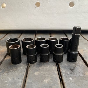 May include: A set of 10 black socket wrenches, including a long extension, arranged on a wooden surface. The wrenches are made of chrome vanadium steel.