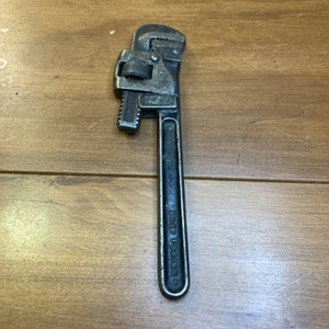 May include: A silver pipe wrench with a black handle. The handle has the text "Drop Forged" on it.