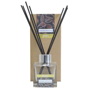 May include: A brown cardboard box with a black and white image of swirling lines. The box has the text "Borders Aromatics" and "Mocha" printed on it. A clear glass bottle with a silver cap and black diffuser sticks is in front of the box. The bottle has a label that says "Mocha" and "Borders Aromatics".