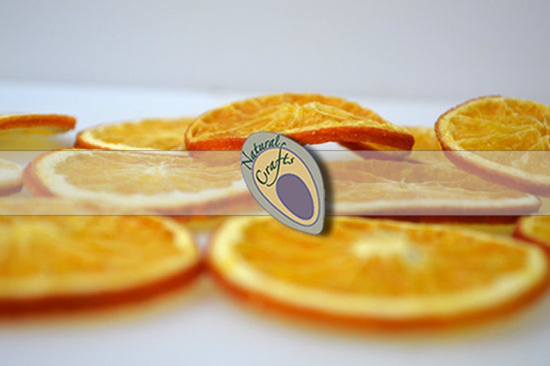 May include: Dried orange slices, a natural craft, arranged on a white surface. The slices are a vibrant orange color and have a slightly translucent appearance.