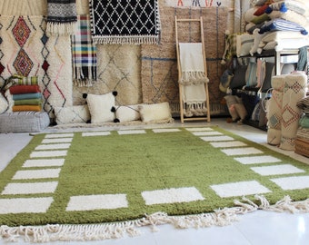 May include: A green rug with a white border and a pattern of white squares. The rug has fringe on all sides.