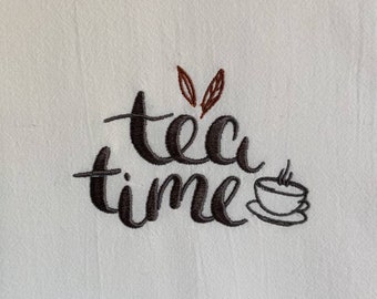 May include: Embroidered tea towel with the text "tea time" in black cursive font and a small brown teacup with steam coming from it.