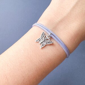 May include: A lavender cord bracelet with a silver butterfly charm.