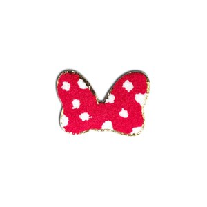 May include: A red bow with white polka dots and a gold glitter outline. The bow is a classic design, perfect for hair accessories or crafting projects. The bow is set against a white background.