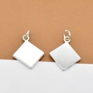 May include: Two silver diamond-shaped charms with a loop at the top for attaching to a necklace or bracelet.