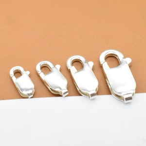 Może przedstawiać: Cztery srebrne zapięcia typu klamra homara w różnych rozmiarach. Zapięcia są popularnym elementem biżuterii do naszyjników, bransoletek i innych projektów jubilerskich.