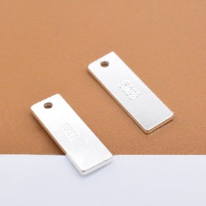 May include: Two silver rectangular tags with a hole at the top. The tags are blank and have a subtle shine.