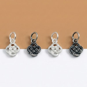 May include: Four silver-toned charms with a Celtic knot design. Two charms are bright silver, and two are oxidized to a darker gray. Each charm has a small loop at the top for attaching to a chain or bracelet. The charms are displayed against a brown and white background.