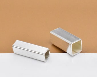May include: Two silver metal square tube end caps. The caps are hollow and have a square opening on each end.