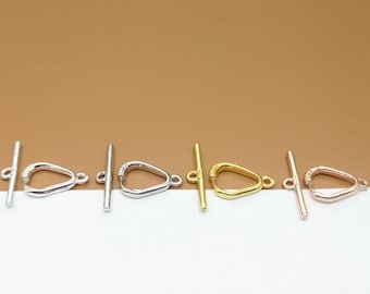 May include: Four toggle clasps in different metal finishes: silver, gold, rose gold, and silver. Each clasp features a heart-shaped loop and a straight bar.