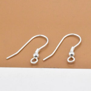 Pode incluir: Dois ganchos de brinco de prata com uma pequena bola na ponta de cada gancho.