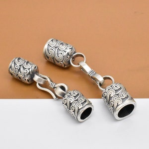 Può includere: Due tappi terminali in metallo argentato per una collana o un braccialetto. Ogni tappo presenta un motivo a spirale dettagliato e un piccolo anello per il fissaggio a una catena.