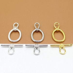 May include: Three silver and gold toggle clasps with a knotted loop. The clasps are designed for jewellery making and have a round shape.