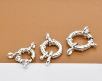 May include: Three silver-toned metal clasps for jewelry making. Each clasp has a round shape with a twisted design.