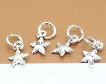 May include: Four silver-colored star charms with attached jump rings. Each star has five points and the text "S925" is visible on the back. The charms are designed for jewelry making.