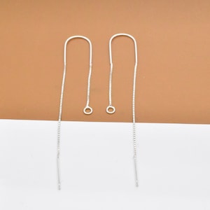 Puede incluir: Un par de pendientes de cadena de plata con un diseño sencillo. Los pendientes son largos y delgados, con un pequeño bucle en la parte superior.