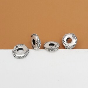 May include: Four silver-toned metal beads with a decorative design and a hole in the center. The beads are marked with the numbers "5925", "5925", "5925", and "5925".