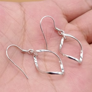 May include: A pair of silver earrings with a twisted, diamond-shaped design. The earrings have a simple hook closure.