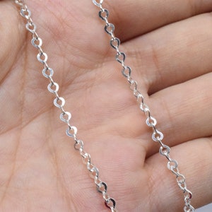 May include: A silver chain necklace with a delicate, oval-shaped link design.