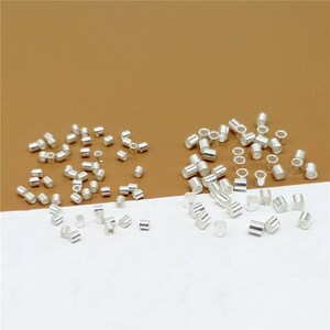 May include: A collection of silver-toned metal jump rings, ideal for jewelry making. The jump rings are arranged in two groups on a white surface.