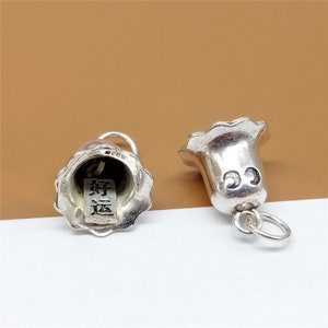 Op de afbeelding: Twee zilveren bellen met een decoratief ontwerp. Een bel heeft de Chinese karakters "新年快乐" aan de binnenkant.