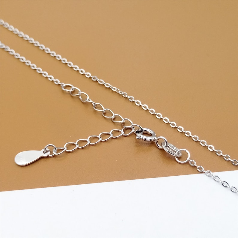 Op de afbeelding: Een zilveren ketting met een karabijn sluiting en een klein, traanvormig hangertje.