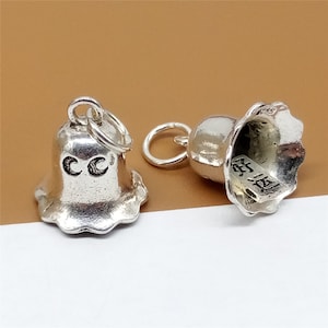 Op de afbeelding: Twee zilveren belcharms met een lus om aan een ketting of armband te bevestigen. Een bel heeft de letters "CC" gegraveerd op de voorkant en de andere bel heeft Chinese karakters gegraveerd aan de binnenkant.