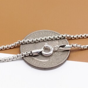 May include: A silver chain necklace with a lobster clasp. The chain is laid on top of a US quarter for size comparison.