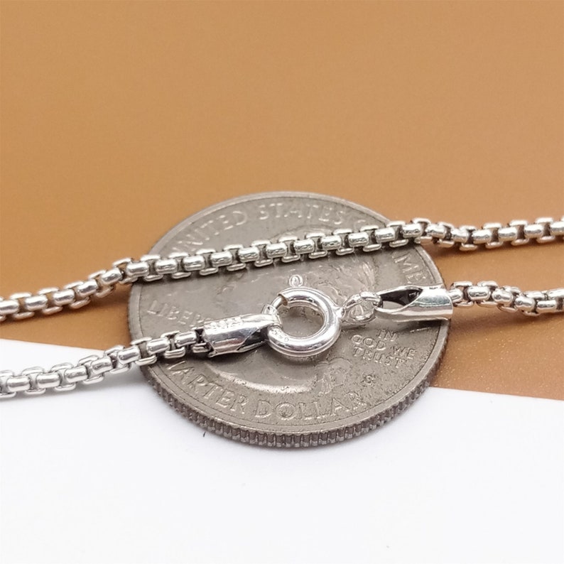 May include: A silver chain necklace with a lobster clasp. The chain is laid on top of a US quarter for size comparison.