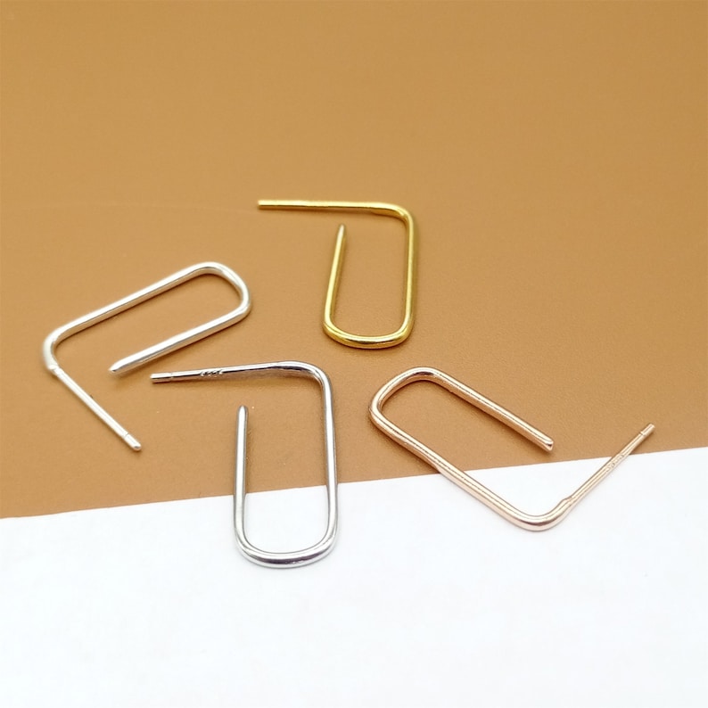 May include: Four earring hoops in different colors: gold, silver, and rose gold. The hoops are all the same size and shape, and they are arranged in a semi-circle.