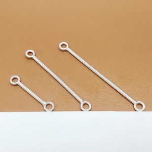 May include: Three silver jump rings with a straight bar connecting the rings. The rings are different sizes.