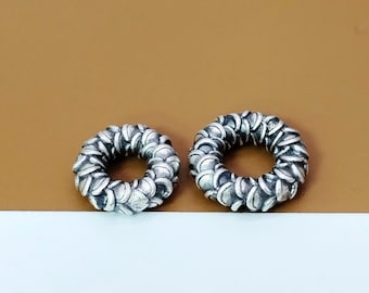 May include: Two silver rings with a textured, scaly design. The rings are round and have a hole in the center.