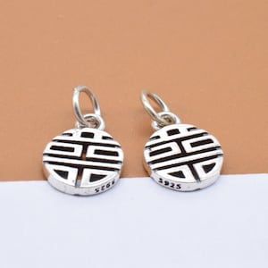May include: Two silver charms with a circular design featuring a Chinese symbol. The charms are marked with "S925" on the back.