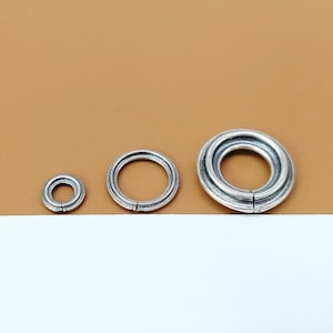 May include: Three silver jump rings of different sizes. The largest ring is double-layered.